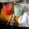 paintbrushes and water cups used for clean-up containing red and aqua water